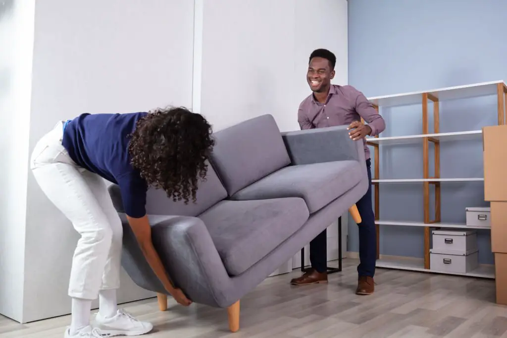 Couple Placing Sofa In Living Room