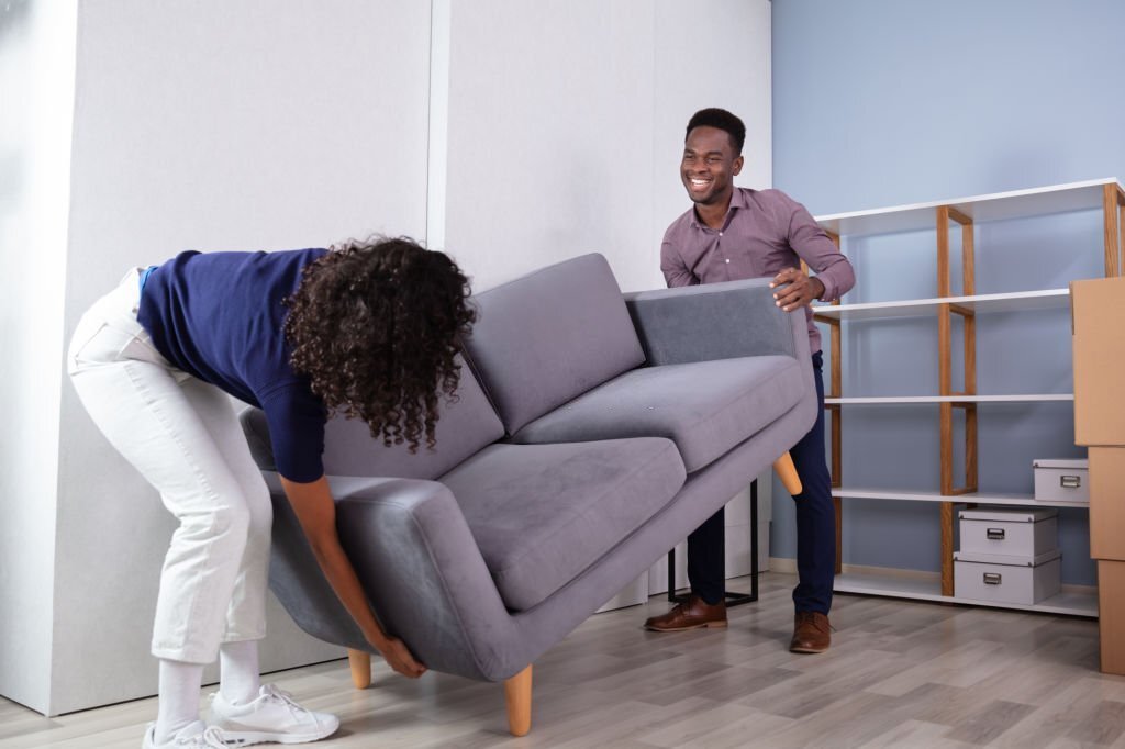 Couple Placing Sofa In New Living Room