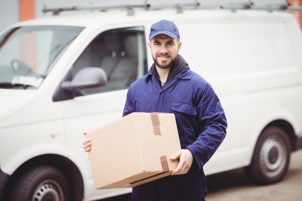 Delivery man holding box in front of his van