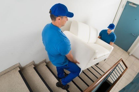 High Angle View Of Two Male Movers Carrying Sofa On Staircase Of House