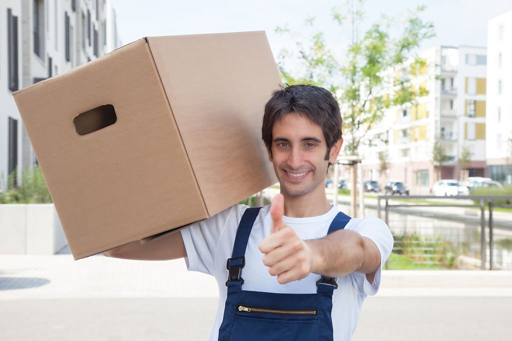 Hispanic removal man showing thumb up with residential area in the background