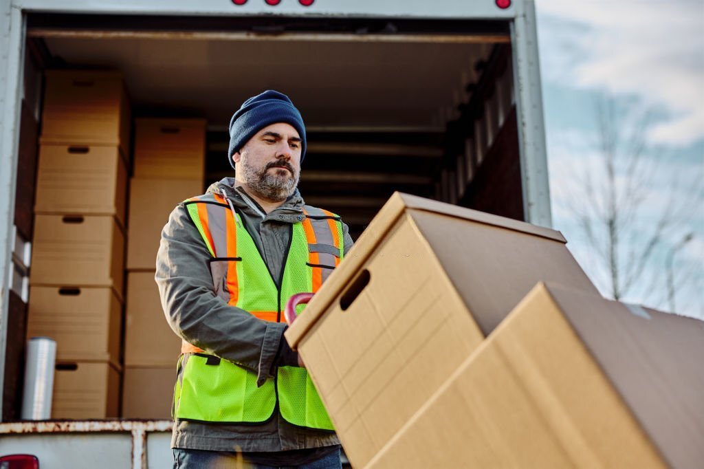Male courier unloading the shipment out of the truck.