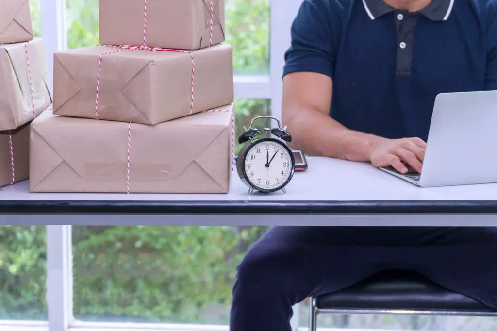 delivery man table with packaging box, laptop and phone while management deliver