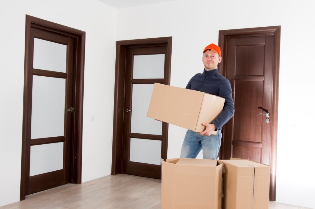 Relocation services man with cardboardboxes. Worker transporting things in the apartment. Moving to a new house concept. Mover with cardboardbox